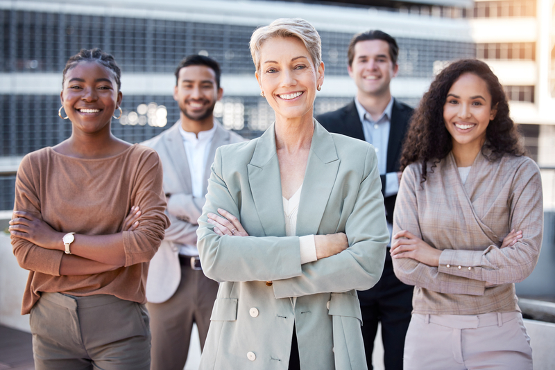 a diverse group of businesspeople standing together in the city with their arms.